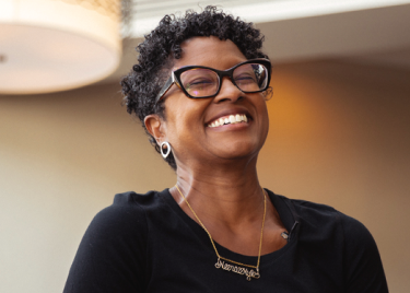 A smiling woman wearing a black shirt and glasses.