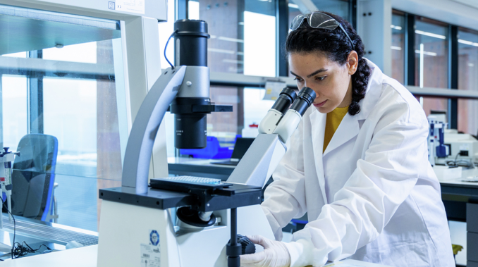 A Gilead employee looking into a microscope