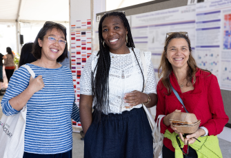  Three women standing in front of scientific posters. 