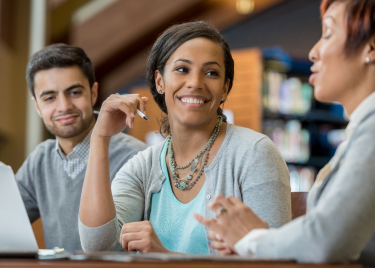 Three people sitting together, working. 