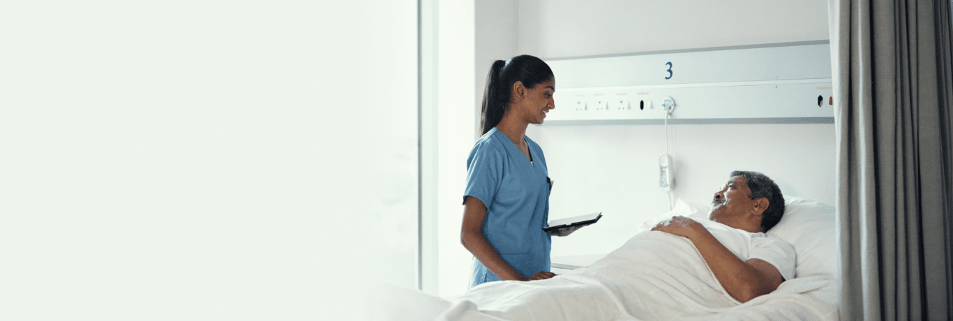 Healthcare provider speaking to patient laying on a hospital bed.