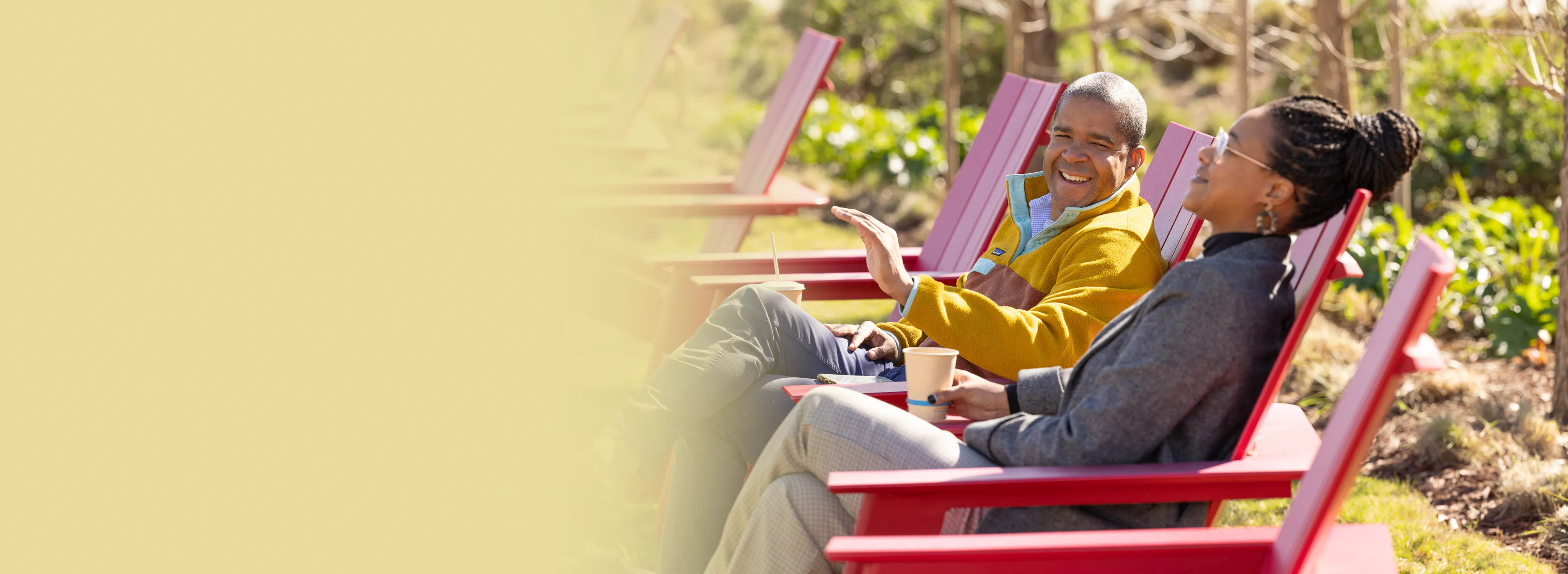 A woman and man sitting in red chairs outside on the Gilead campus