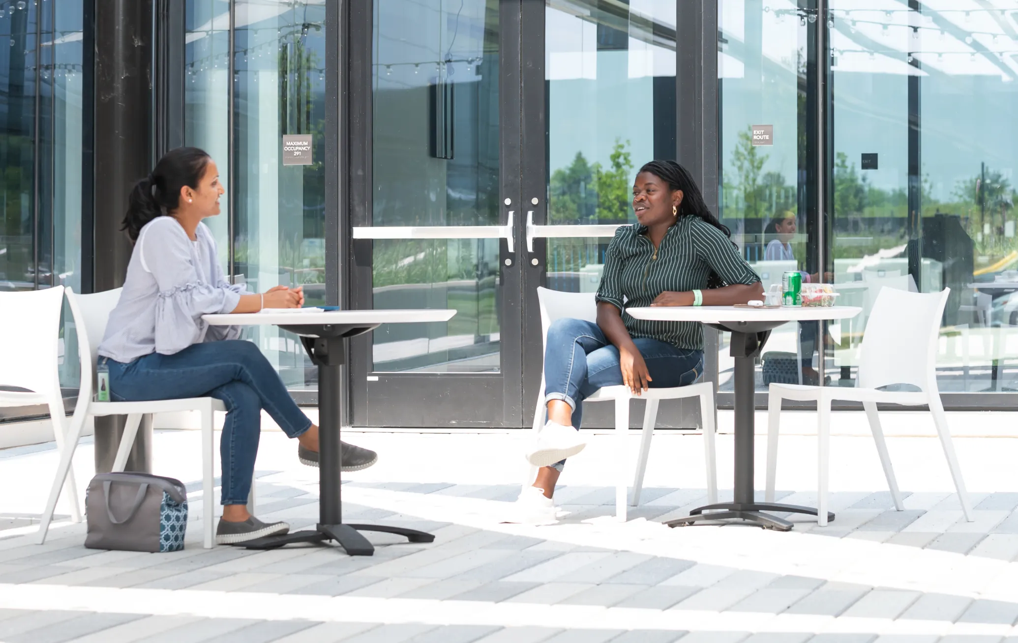 Two women sitting outside glass doors conversing