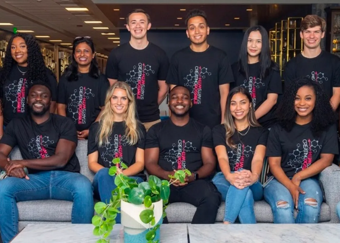 A group of about 18 interns wearing matching t-shirts