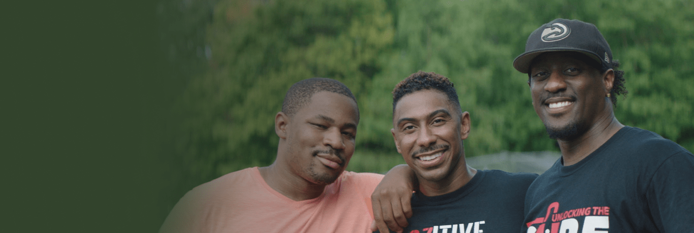 Three young Black men smiling together.