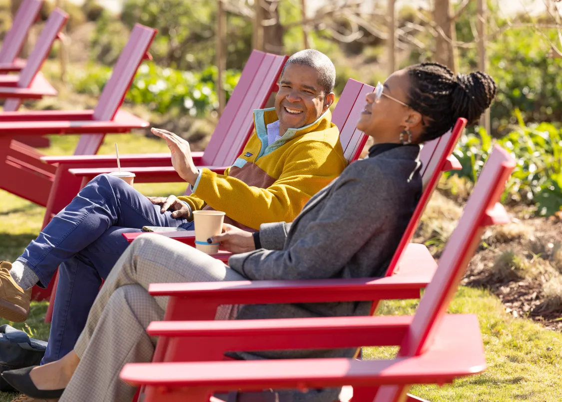 A woman and man sitting in red chairs outside on the Gilead campus