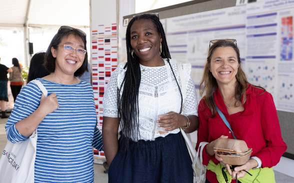 Three women standing in front of scientific posters. 