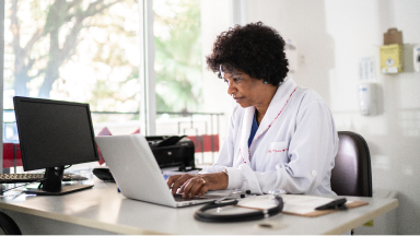 Woman with white coat working on a computer