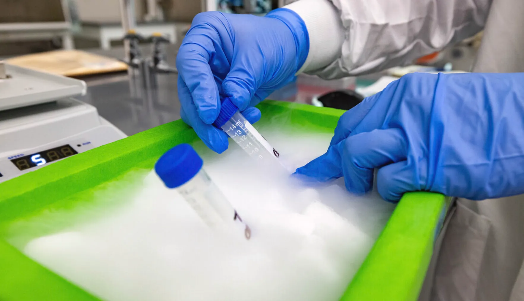 A gloved hand holding a beaker in a laboratory