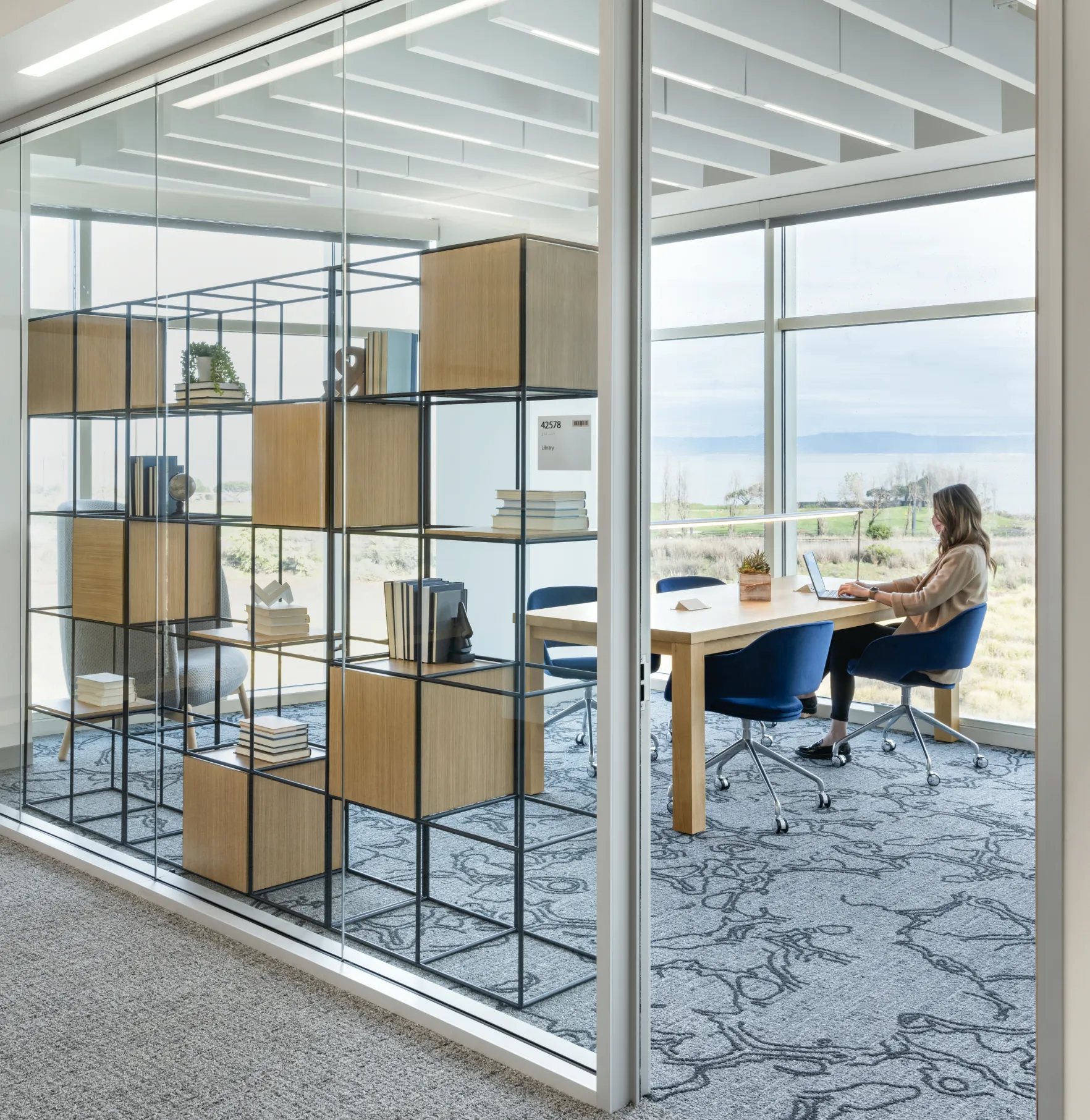 A person working on the  campus in front of a window with a view to the Bay