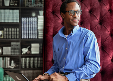 A man wearing glasses in front of a bookshelf