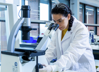 A  employee looking into a microscope