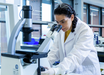 A Gilead employee looking into a microscope