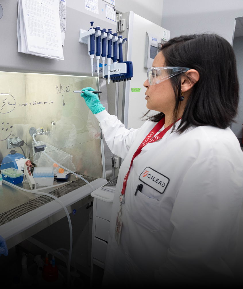 A scientist writing on a wall board in a lab.