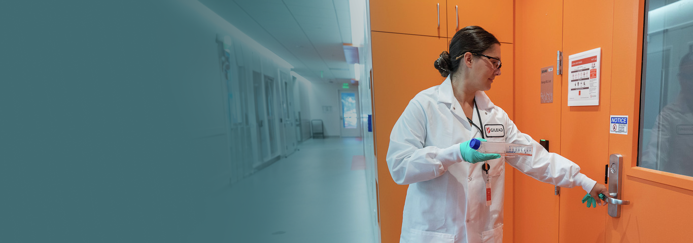 A woman wearing a white lab coat, smiling.